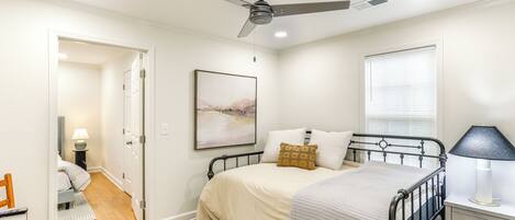A bedroom with a bed, bedside table, lamp, and a ceiling fan.