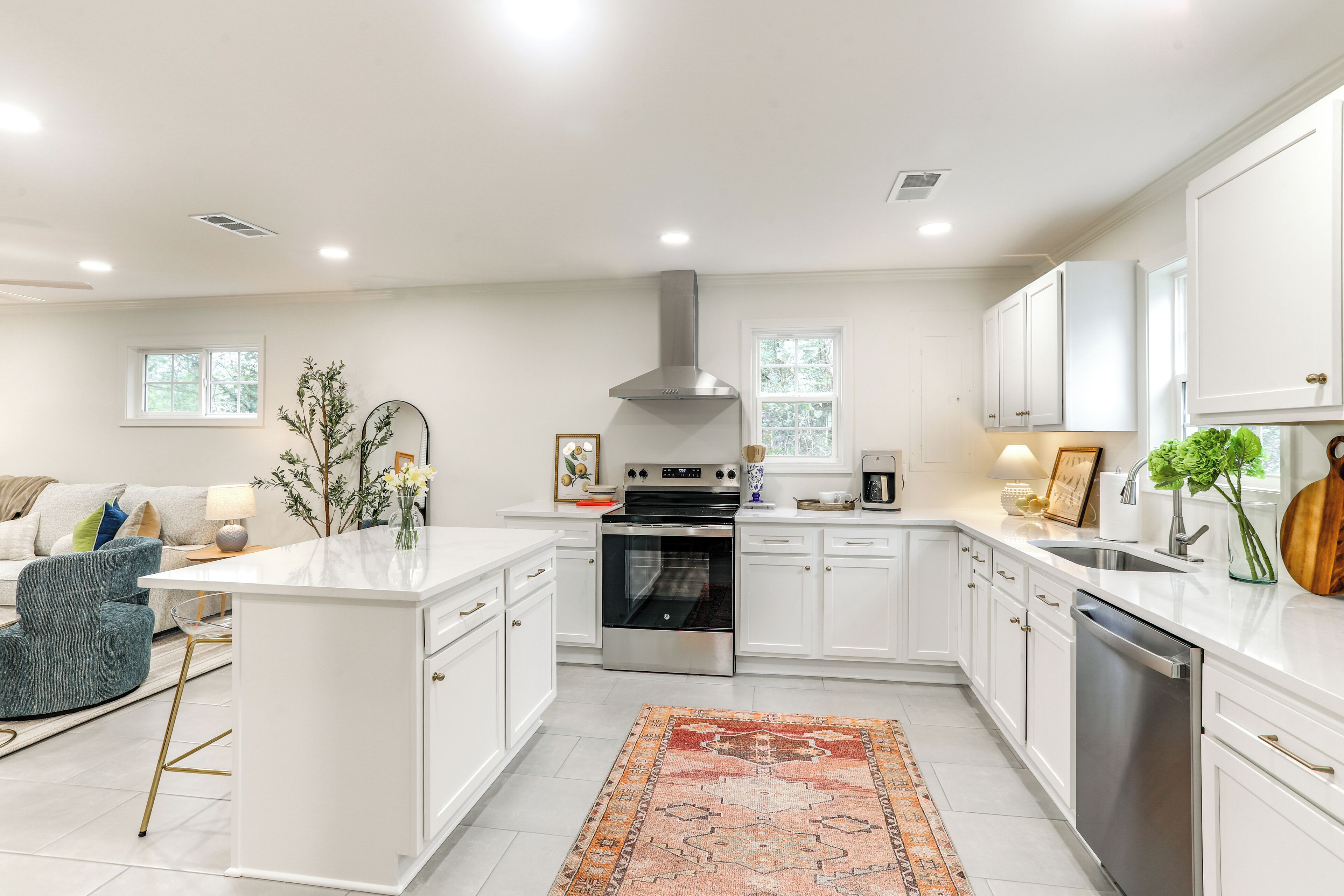 Una cocina moderna con armarios blancos, electrodomésticos de acero inoxidable y una isla central.