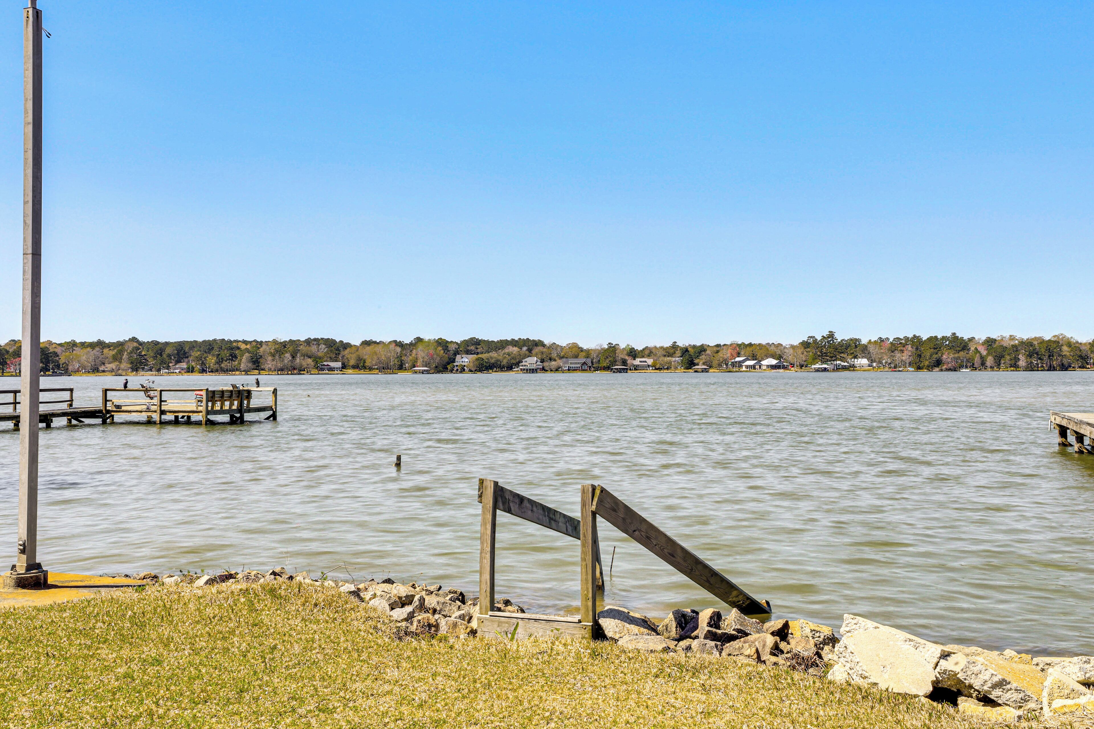 A lakeside view with a dock, a wooden structure, and a clear sky.