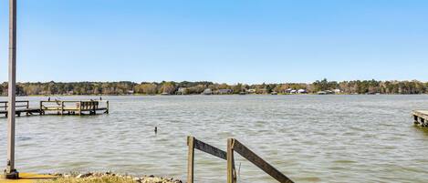 A lakeside view with a dock, a wooden structure, and a clear sky.