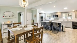A spacious kitchen with a dining area, featuring a wooden table, chairs, and a central island with bar stools. - Lake Moultrie Access: Moncks Corner Home w/ Dock (Moncks Corner)