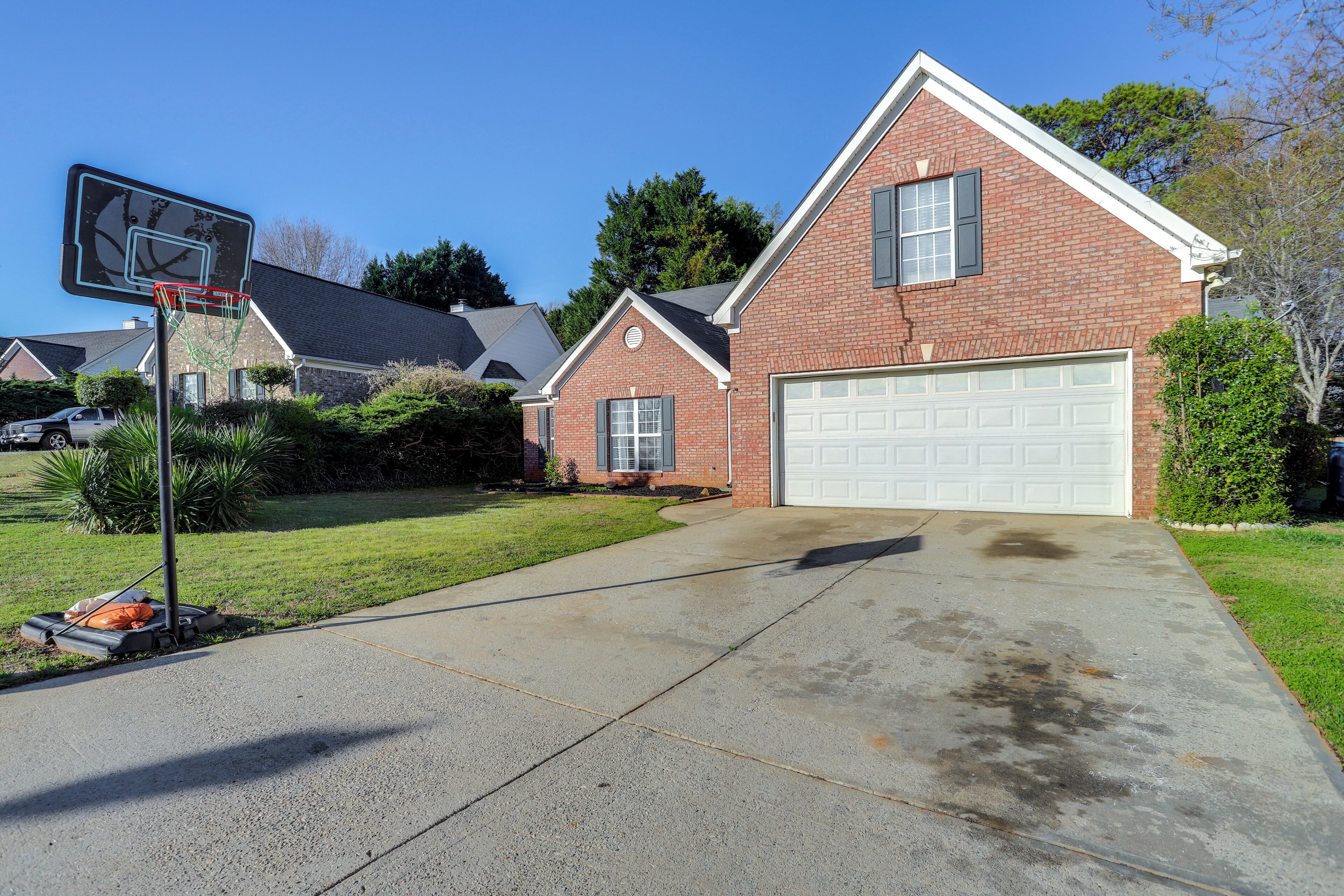 A residential house with a garage, a basketball hoop, and a well-maintained lawn.