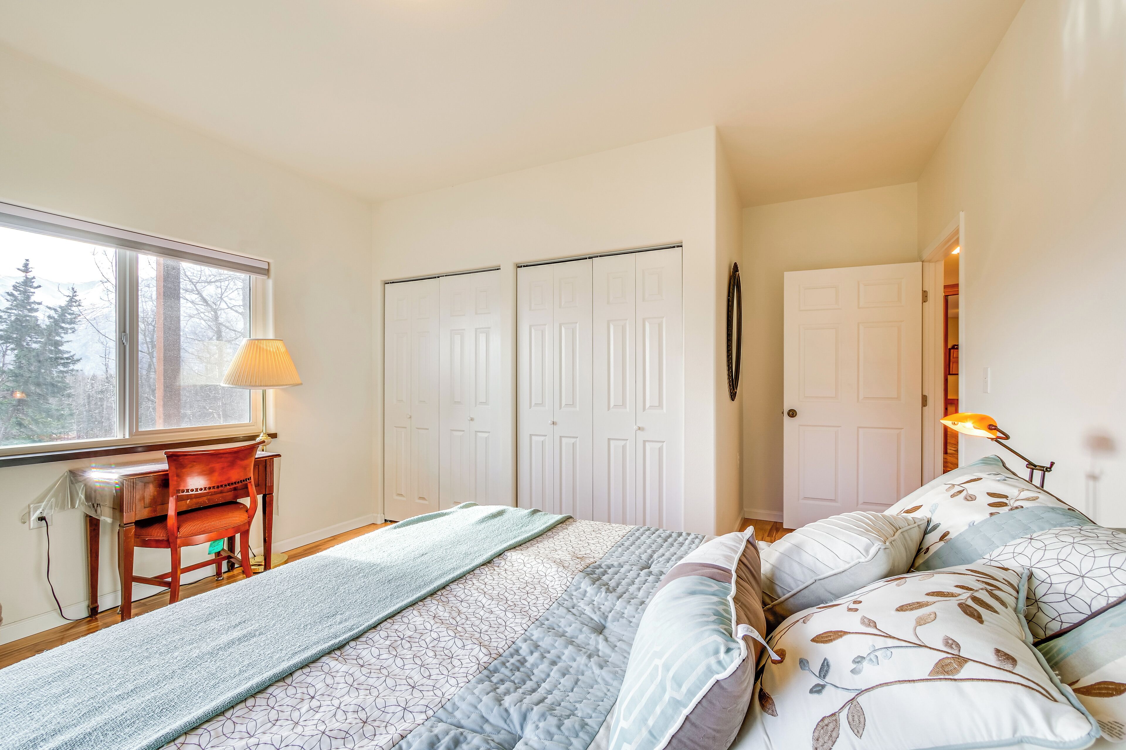 A bedroom with a bed, a desk, and a window.