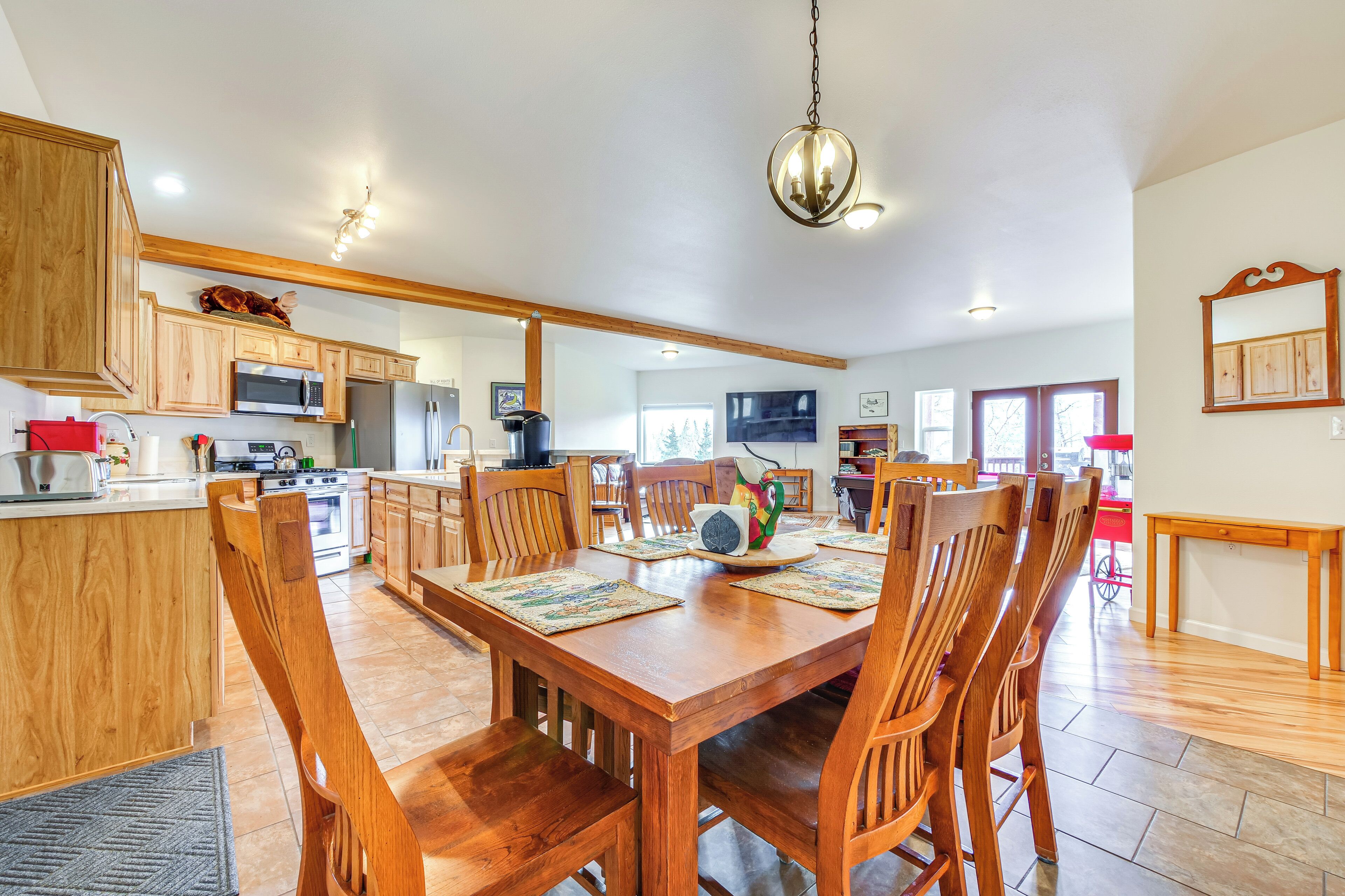 A spacious kitchen with wooden cabinets, a dining table with chairs, and a chandelier.