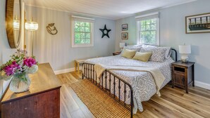 Une chambre à coucher avec un lit, des tables de chevet, un miroir et une fenêtre.