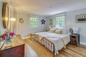 Un dormitorio con cama, mesitas de noche, un espejo y una ventana.