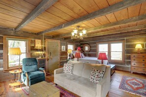 A cozy cabin interior with a wooden ceiling, a sofa, a chair, a bed, and a dresser. - Scenic Hot Springs Retreat Near Appalachian Trail! (Hot Springs)