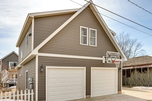 A two-story house with a garage, a basketball hoop, and a white picket fence.