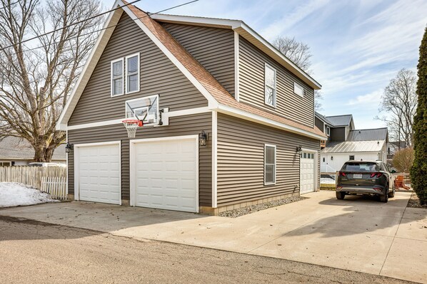 A two-story house with a garage, a basketball hoop, and a driveway.