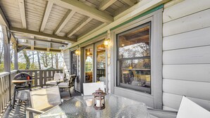 A covered outdoor seating area with a table and chairs, a grill, and a lantern.