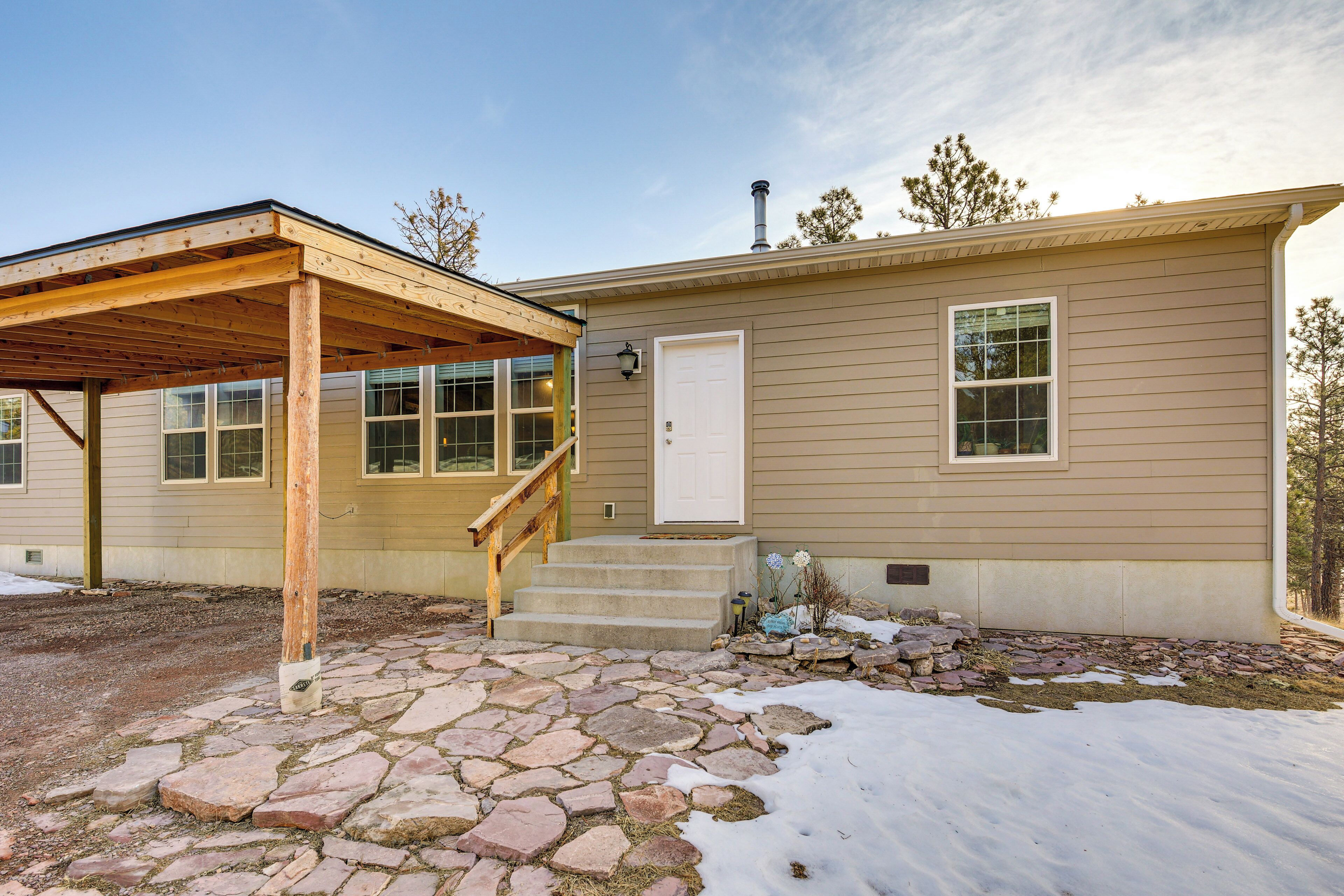 A single-story house with a stone-paved patio, a wooden porch, and a white door.
