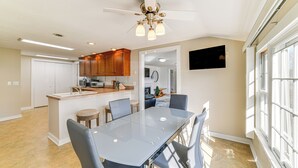 A modern kitchen with a central island, wooden cabinets, and a dining area with a glass table and chairs. - 2 Mi to Suny Cortland: Home Near Hiking & Golf! (Cortland)