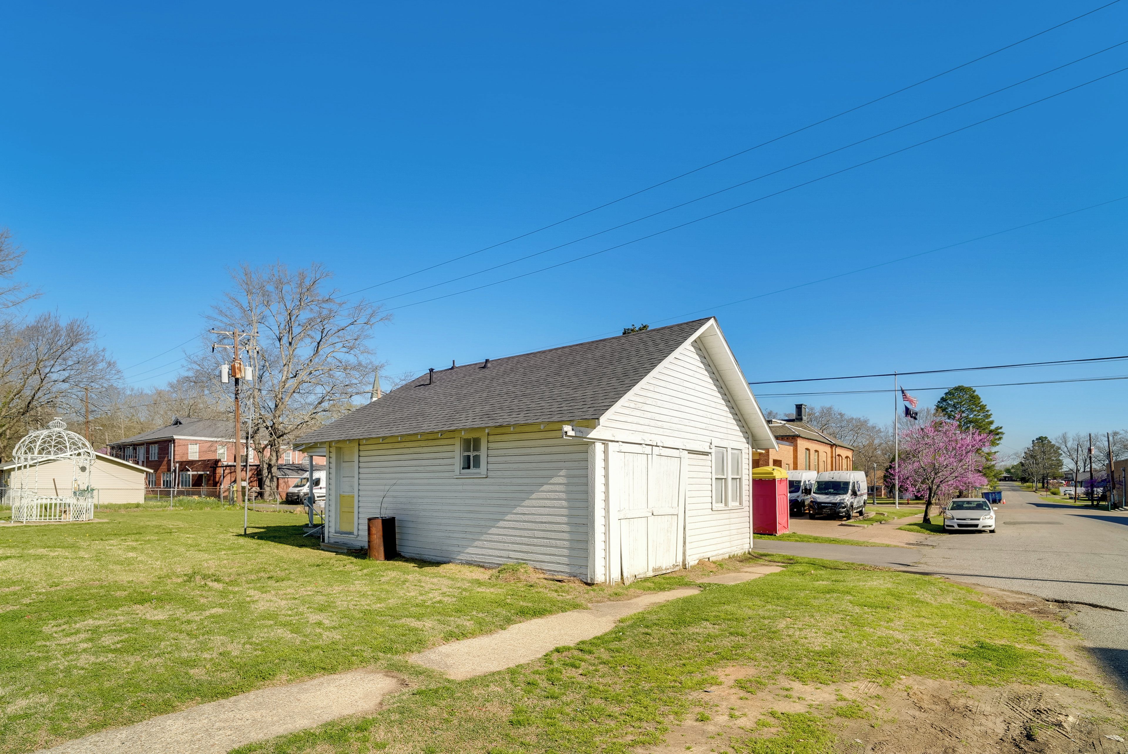 A small, single-story building with a gabled roof, a front porch, and a small attached garage.