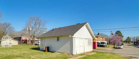 A small, single-story building with a gabled roof, a front porch, and a small attached garage.