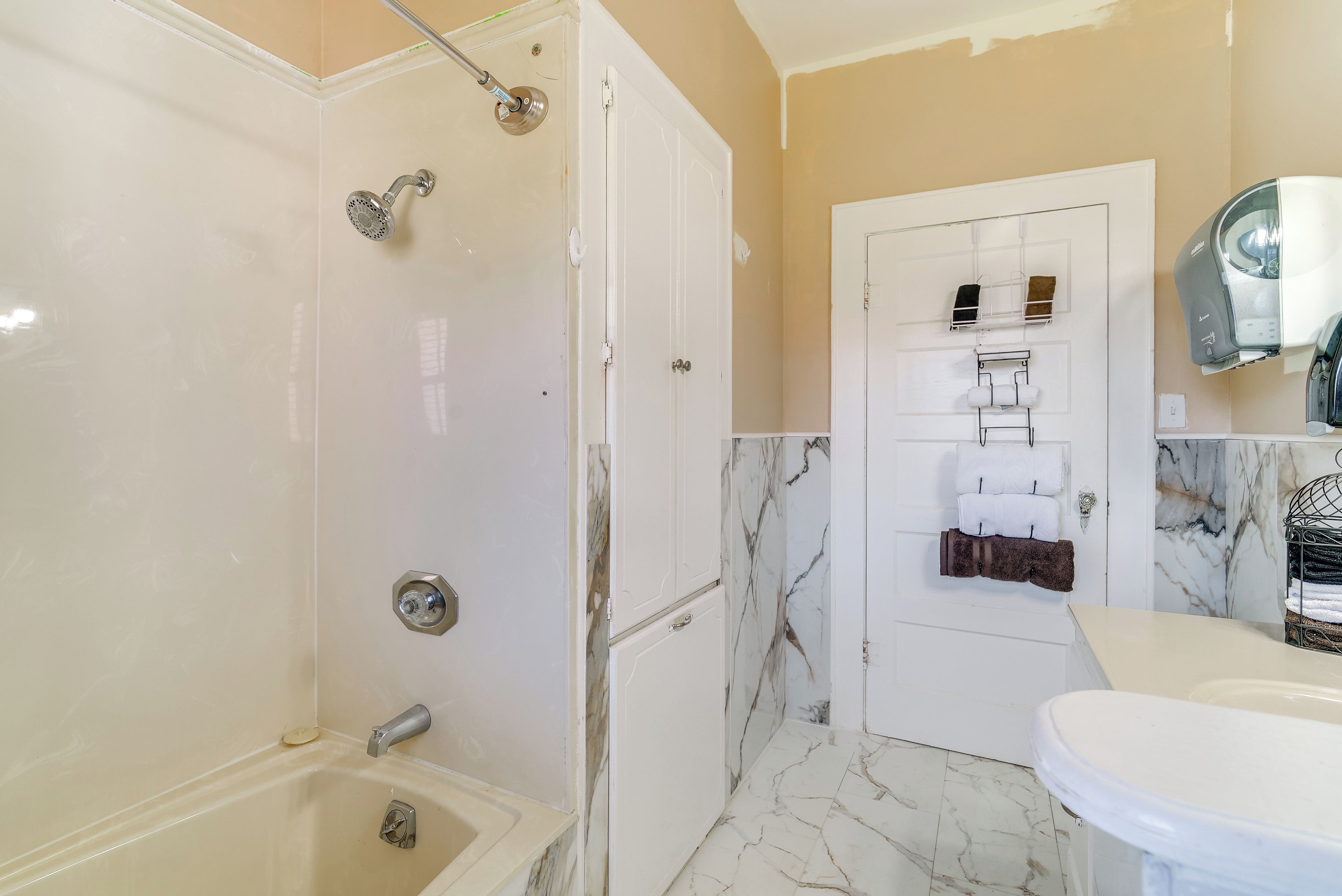 Baño con ducha, inodoro, lavabo y toallero con toallas.