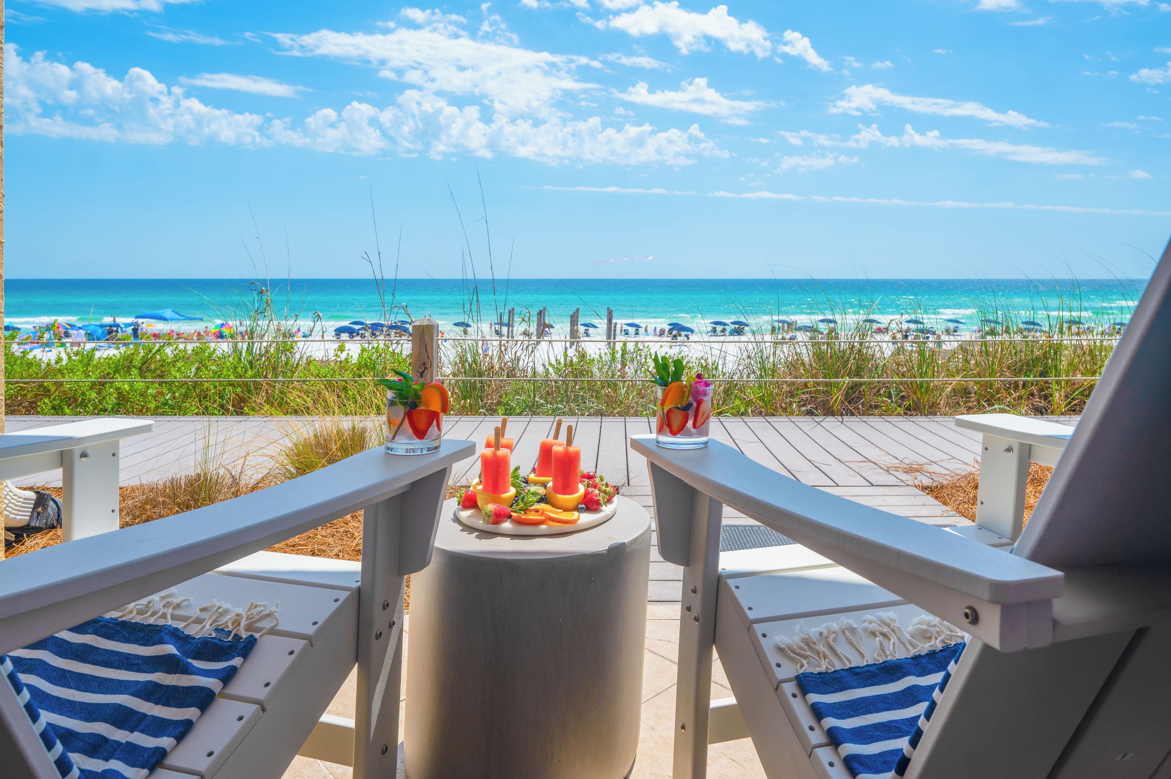 A beach view with lounge chairs and a table with fruit drinks.