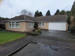 A two-story house with a garage, a front lawn, and a driveway. - Bungalow - Sleeps 6 - Garden - Wheelchair Access (Leicester)