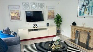 Una sala de estar moderna con televisor de pantalla plana, un sofá, una mesa de centro y una chimenea.