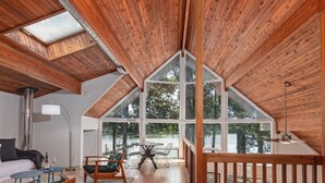 Un espacioso dormitorio tipo loft con techo inclinado, ventanas amplias y vistas al exterior.
