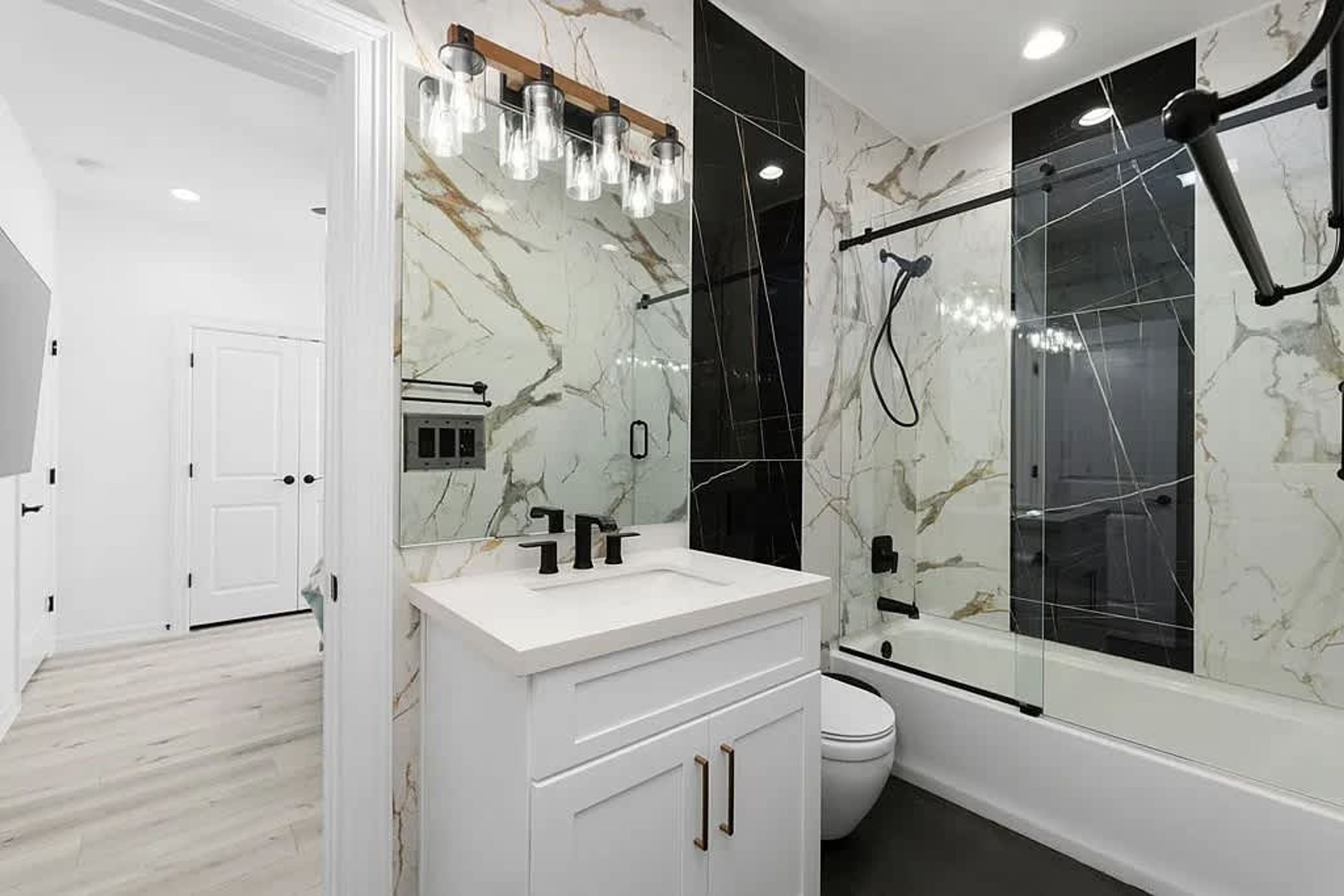 Une salle de bain moderne avec un meuble-lavabo blanc, un grand miroir et une douche séparée par des parois en verre.