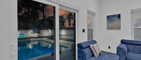A modern living room with a pool, a blue sofa, and a painting on the wall.