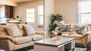 Een woonkamer met een beige leren bank, een bijzettafeltje en een potorkidee.