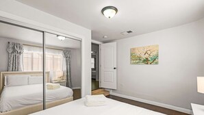 Een hotelkamer met een groot bed, een nachtkastje met een lamp, een spiegel en een schilderij aan de muur.