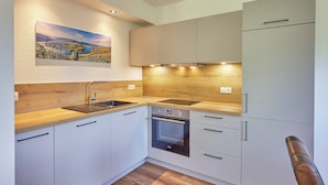 A modern kitchen with white cabinets, a wooden countertop, and a built-in oven.