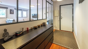 A modern hallway with a large mirror, a wooden floor, a small rug, and a door.