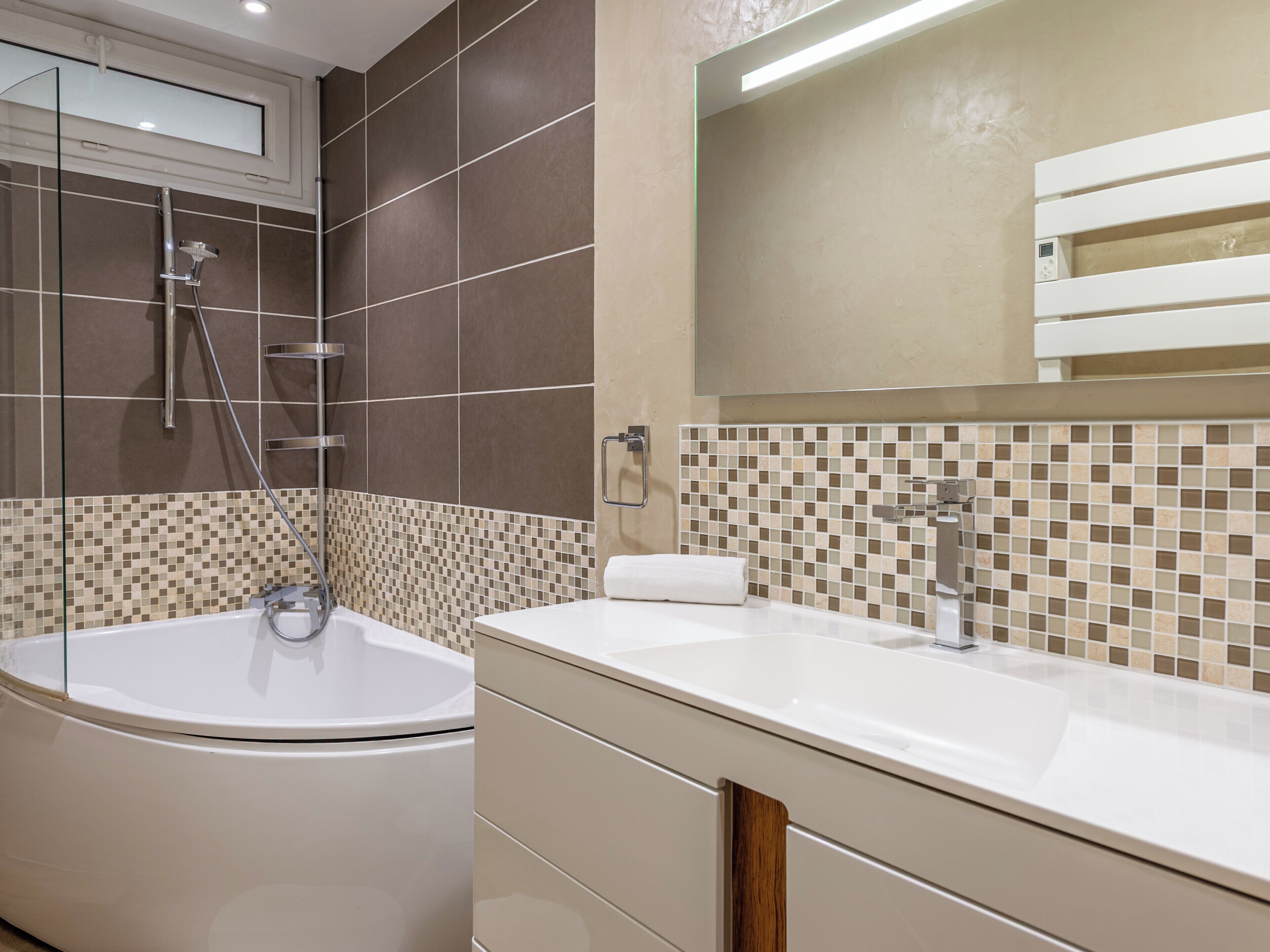 A modern bathroom with a freestanding bathtub, a vanity with a mirror, and a tiled backsplash.