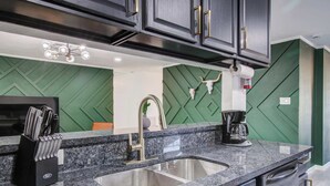 A kitchen with a granite countertop, stainless steel sink, and modern cabinetry.