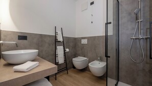 Een moderne badkamer met een vrijstaand wastafelmeubel, een bidet, een toilet en een inloopdouche.