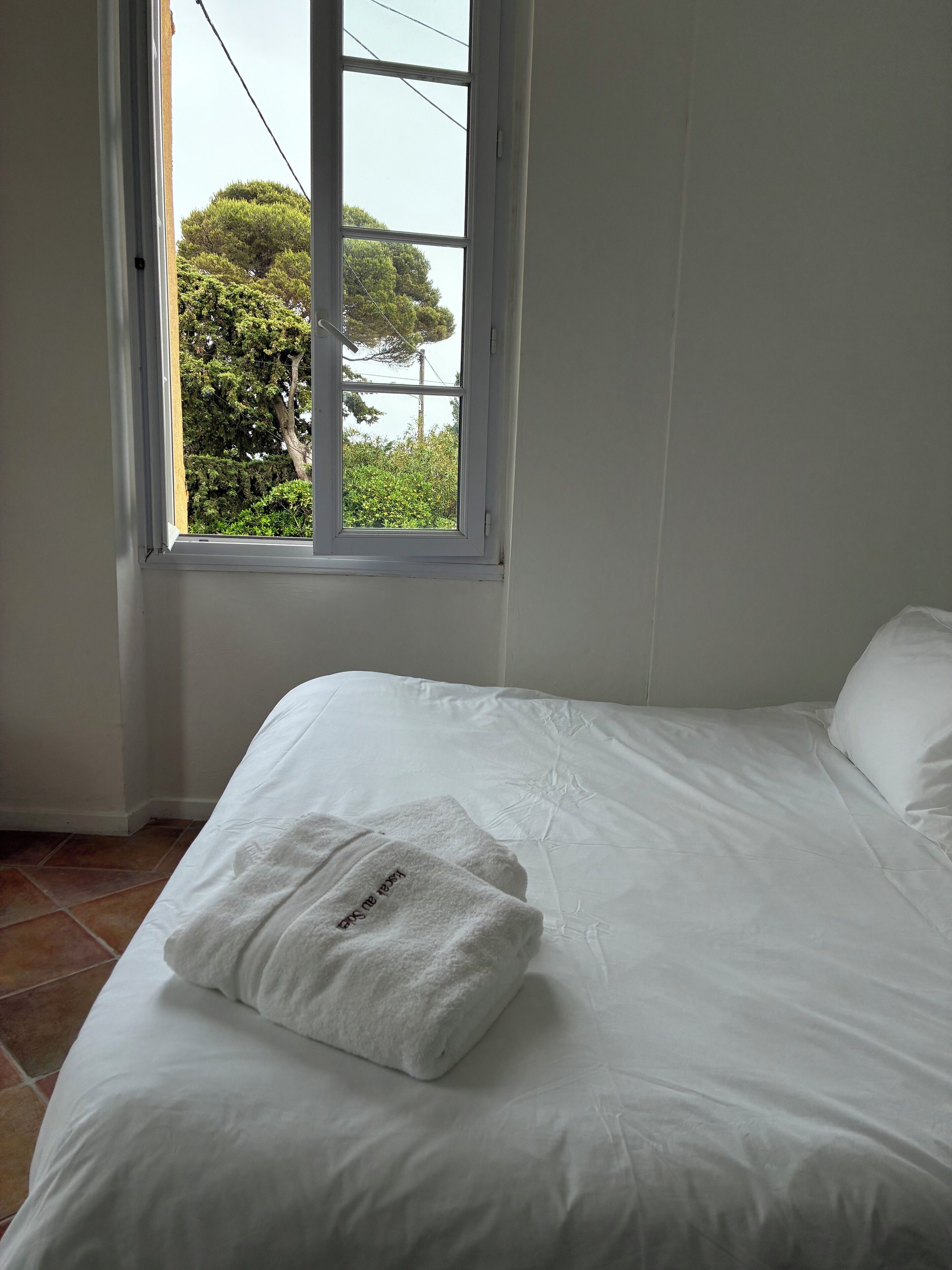 Ein Schlafzimmer mit einem Bett, einem Fenster und Blick auf Bäume.