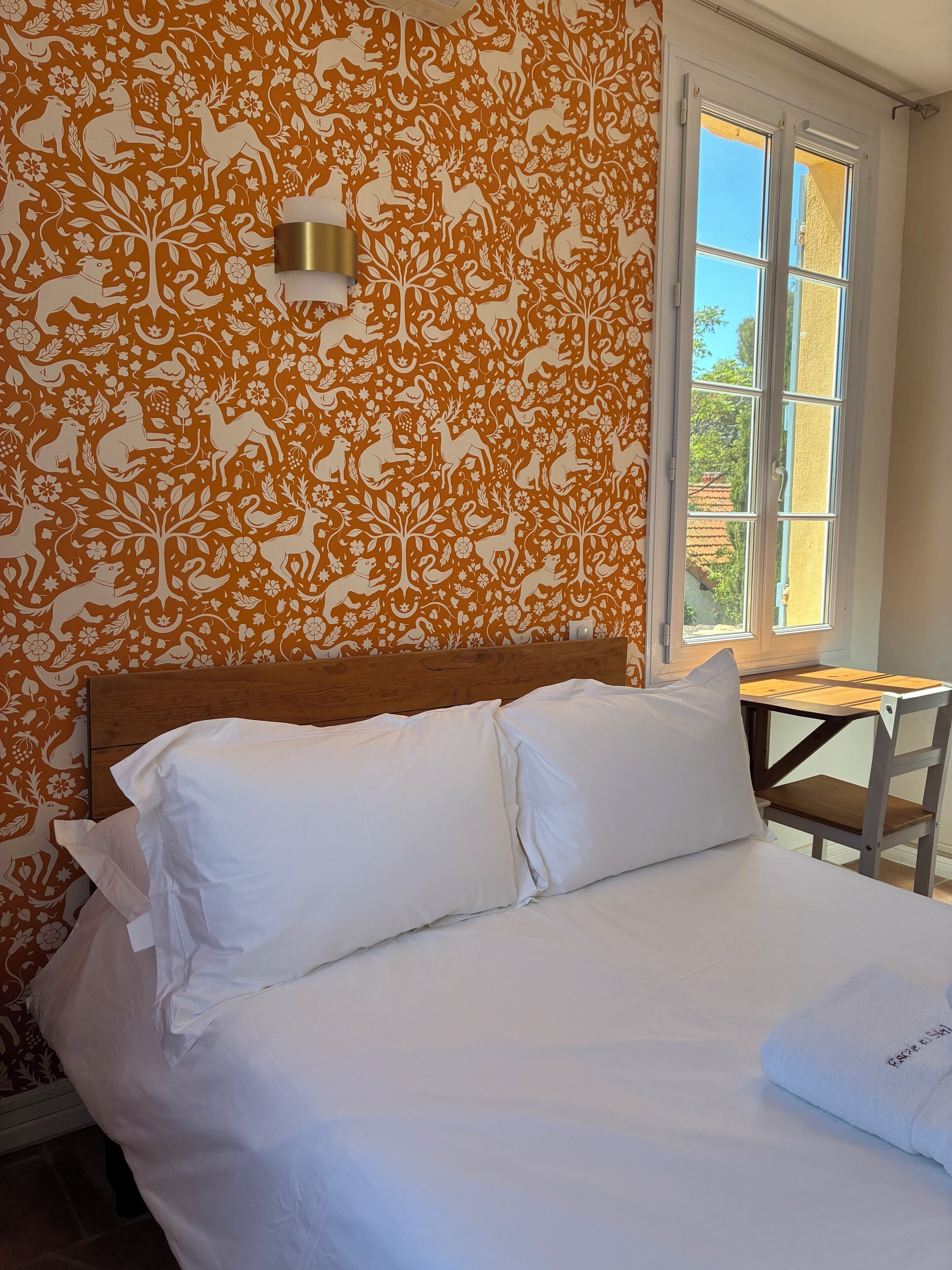Un dormitorio con cama, almohadas blancas y cabecera de madera.
