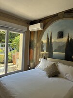 Una habitación de hotel con una cama grande, vistas al exterior y un mural decorativo en la pared.