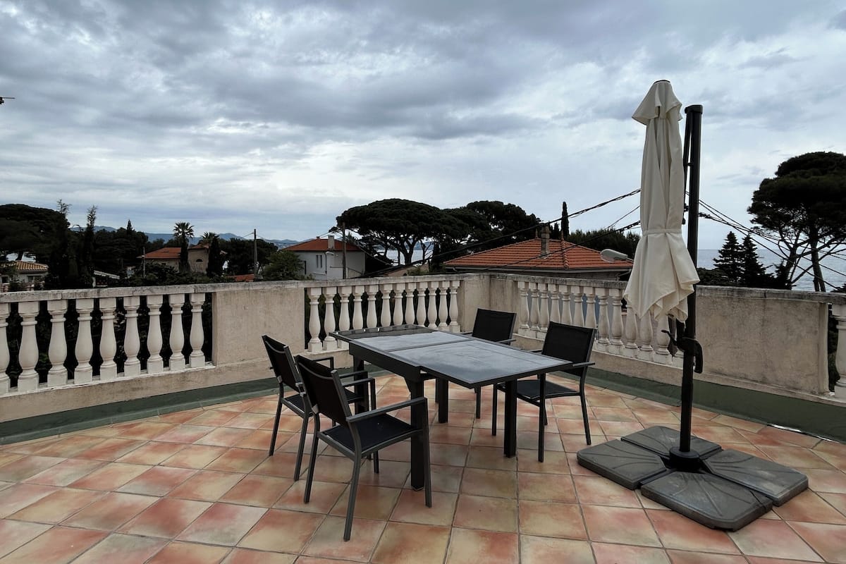 Une terrasse extérieure avec une table et des chaises, un parasol et une vue sur les environs.
