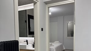 A modern bathroom with a large mirror, a sink, and a black radiator.