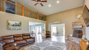A spacious living room with a leather sectional sofa, a large patterned rug, and a fireplace. - Charming 5-bedroom Cadillac Retreat W/ Private Hot Tub Shared Basketball Court (Cadillac)