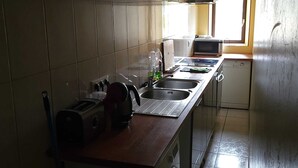 A compact kitchen with a washing machine, a microwave, and a sink. - SPACIOUS 3-BEDROOM APT (APT N°15) (Roanne)