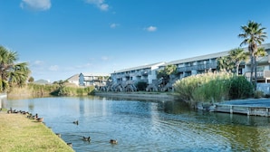 Un hĂŽtel situĂ© au bord de lâeau, dotĂ© dâune piscine, de palmiers et dâun quai.