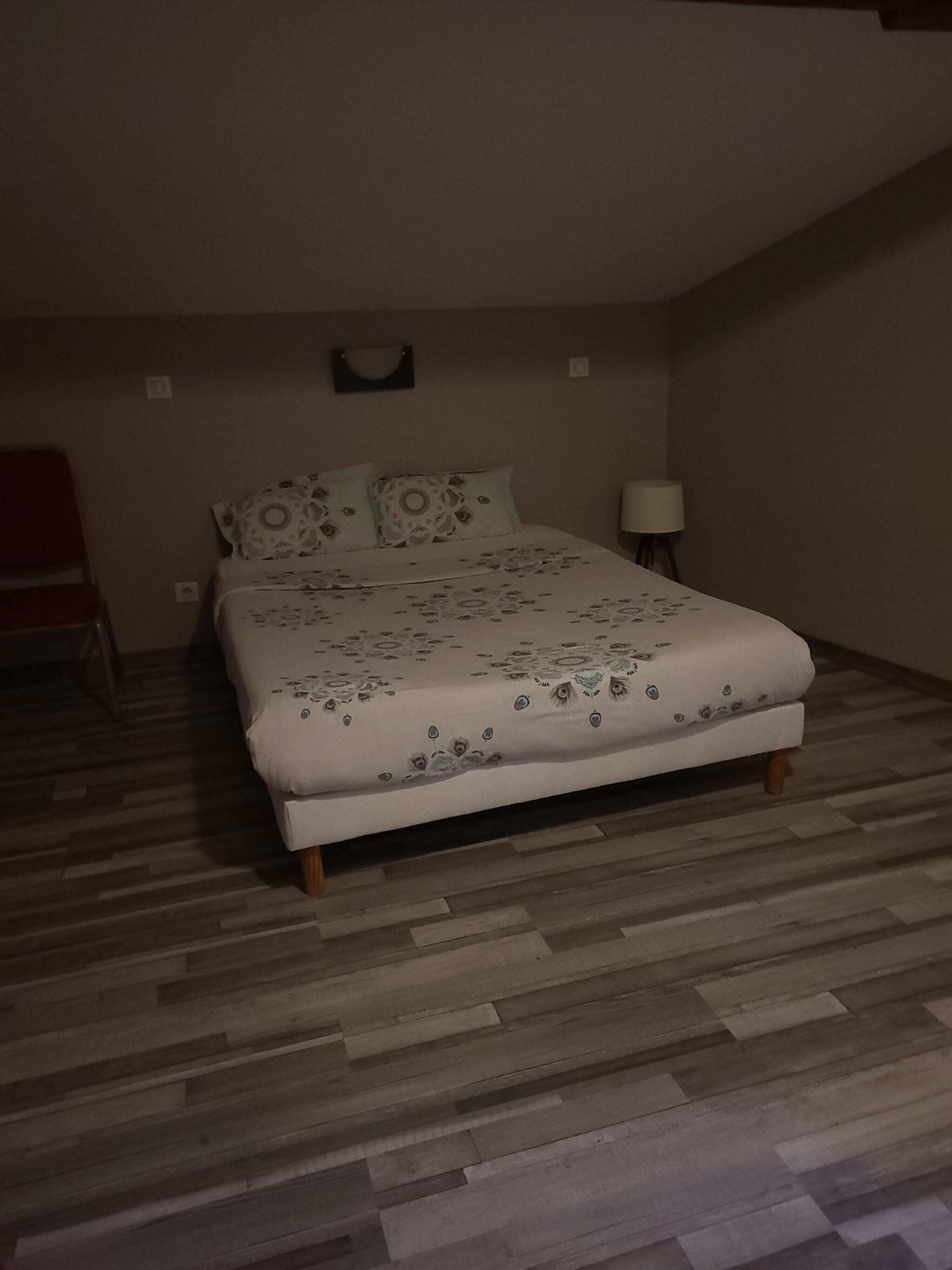 Makuuhuone, jossa on sänky, yöpöytä, lamppu ja tuoli.