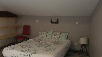 Quarto com uma cama, uma cadeira, um abajur e uma estante.