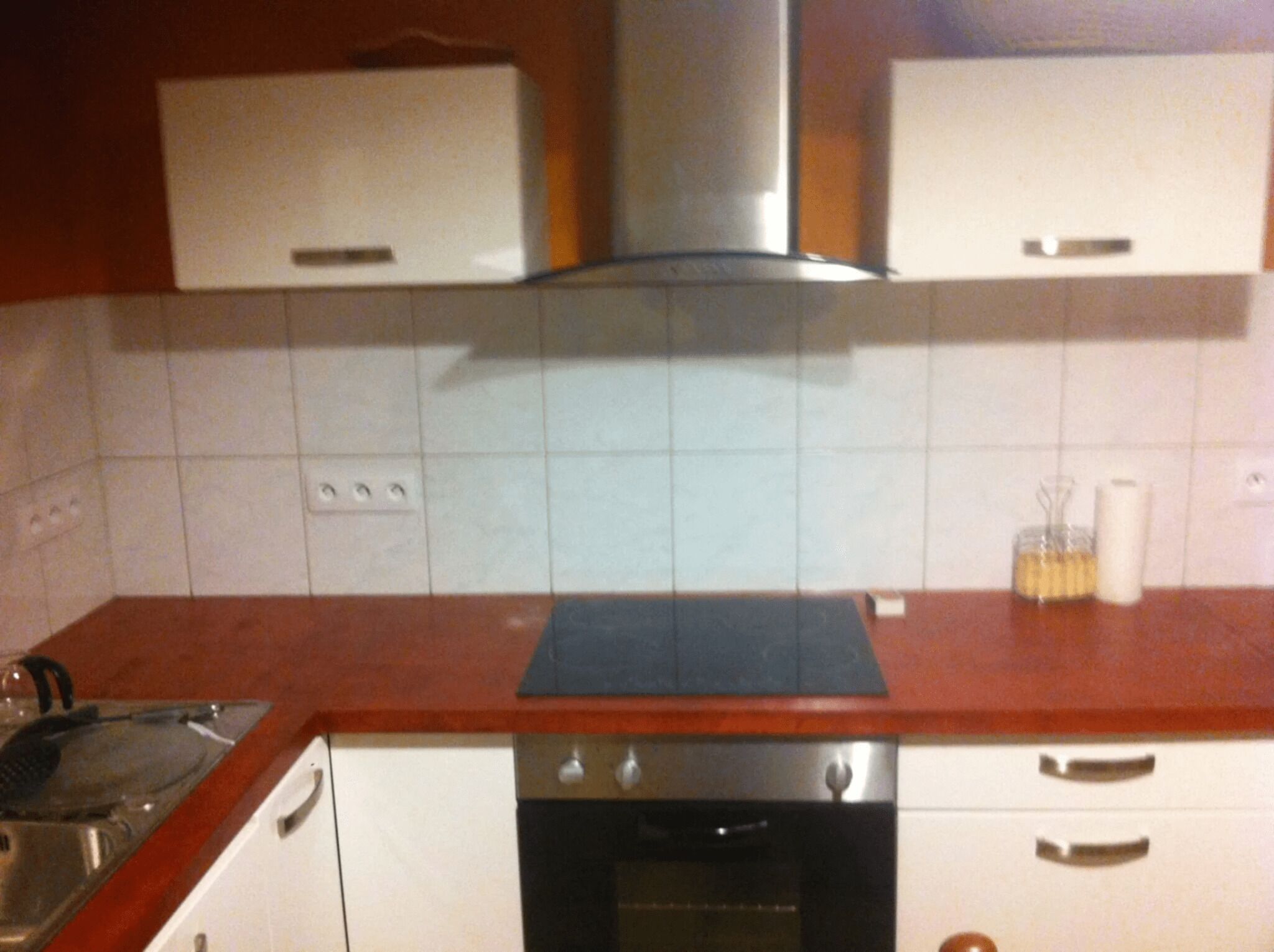 Keittiössä on valkoiset kaapit, ruostumattomasta teräksestä valmistettu liesituuletin, liesi ja työtaso, jonka päällä on vedenkeitin.