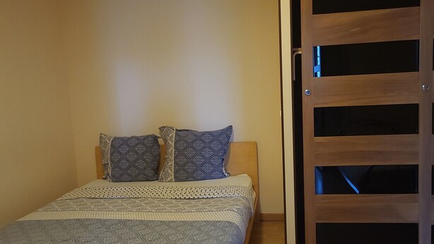 Un dormitorio con una cama, ropa de cama estampada, piso de madera y una puerta corredera.