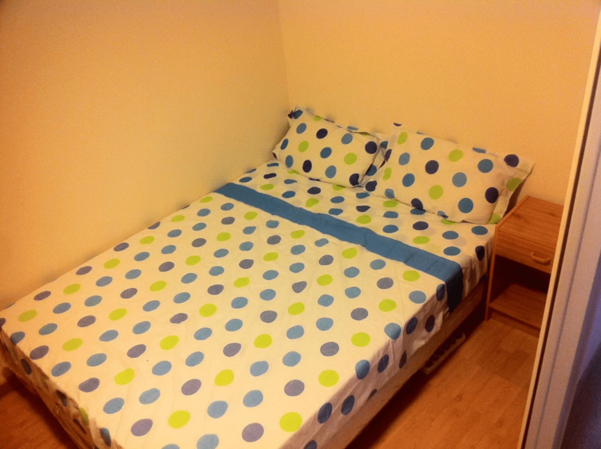 A small, single-bed room with a polka dot bedspread and matching pillow.