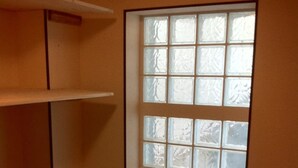 Una habitación con una puerta grande de vidrio esmerilado, piso de madera y una estantería blanca.