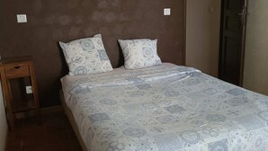 Una camera da letto con un letto, due cuscini, un comodino, una lampada a parete e una porta.