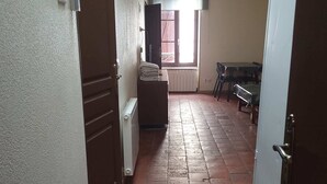 Un corridoio con termosifone, un tavolo con sedie e un frigorifero bianco.