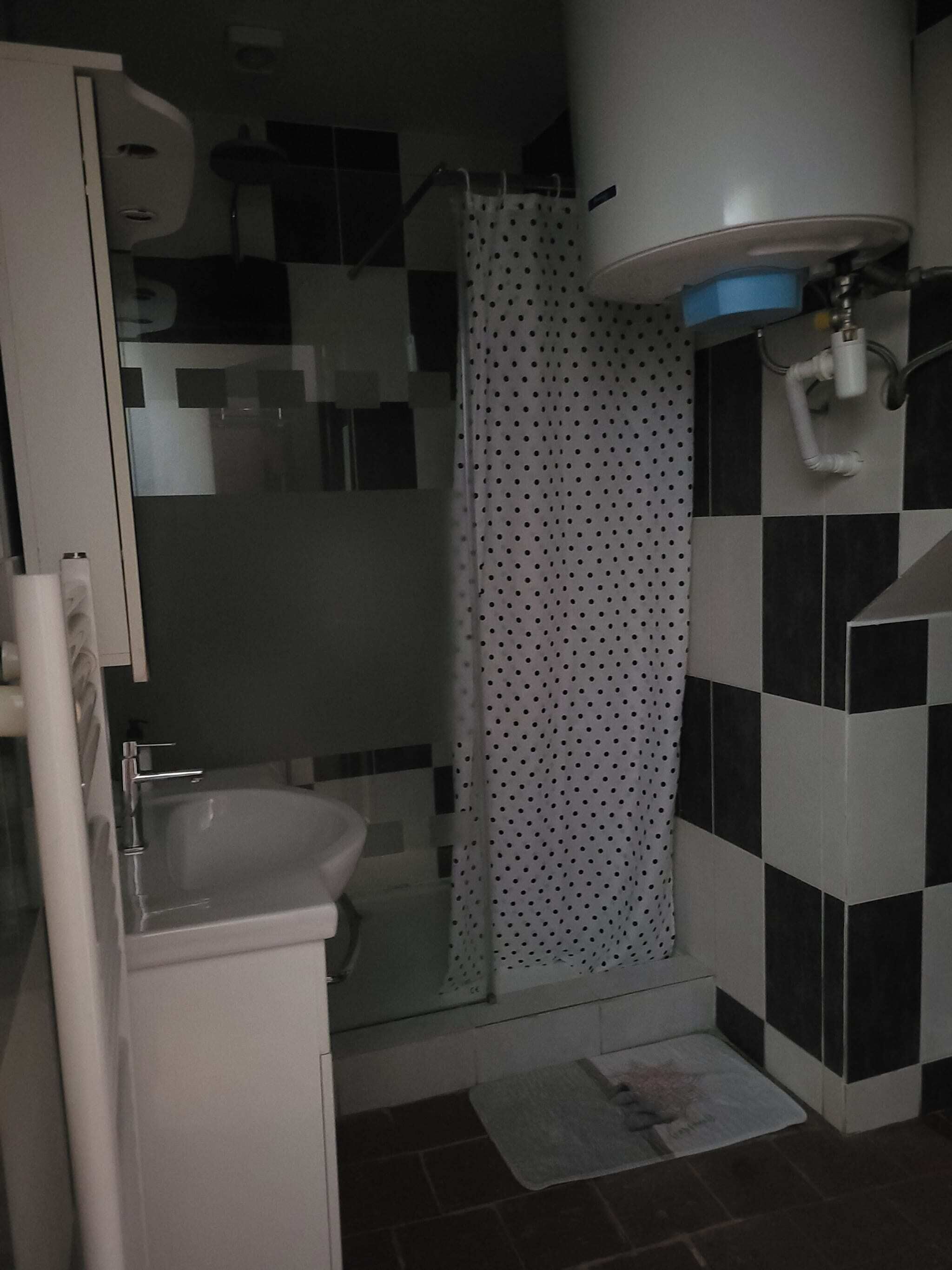 Uma casa de banho com chuveiro em cabine de vidro, lavatório branco e sanita.