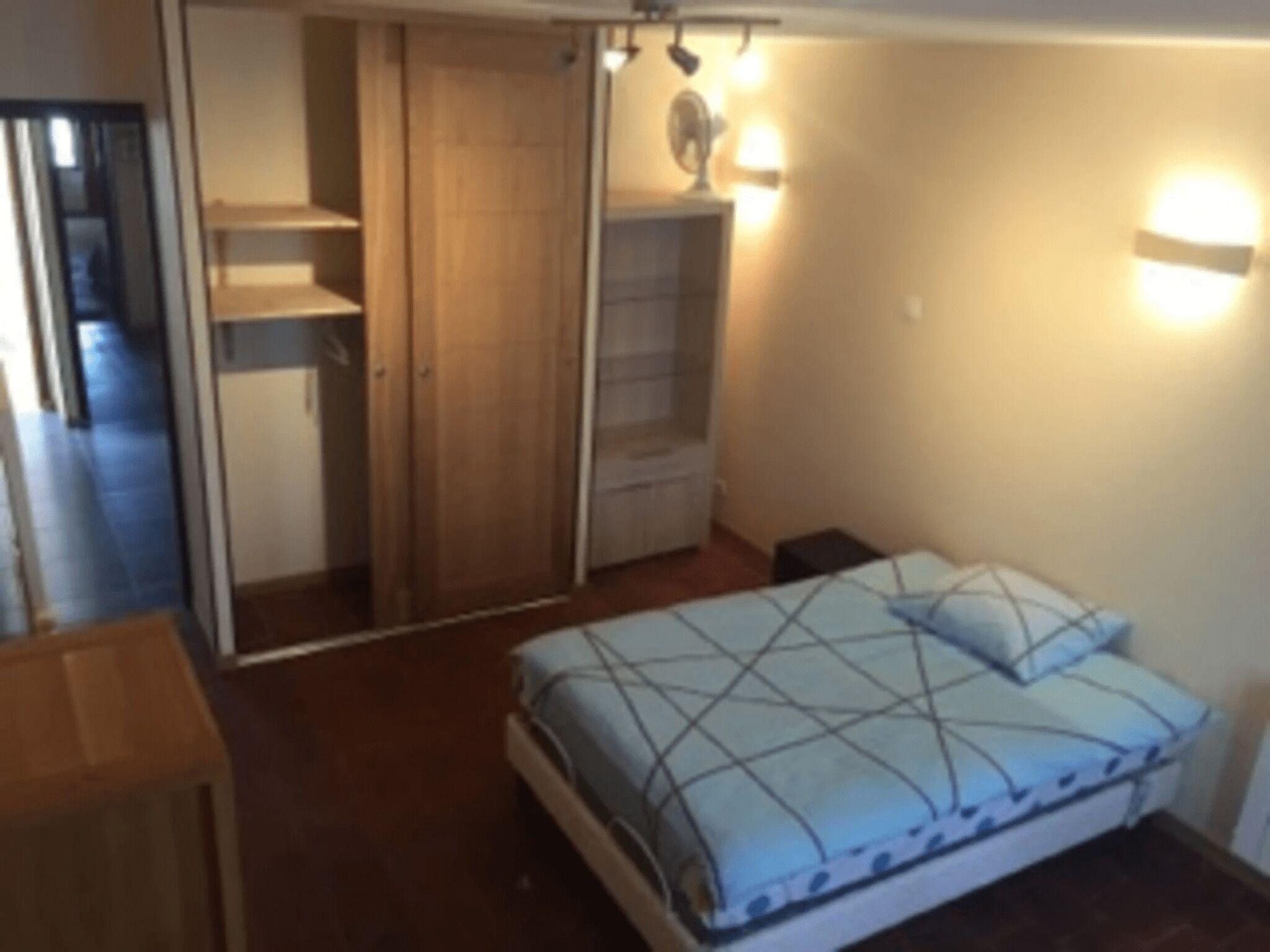 A bedroom with a bed, a wardrobe, and a nightstand.